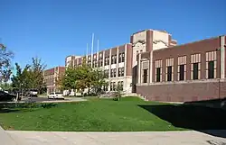 A long, three-story brick school building on top of a hill.