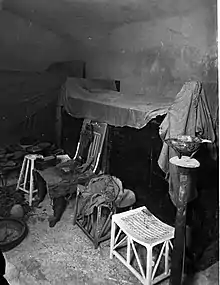 Blank-walled burial chamber with neatly arranged furniture around the sides