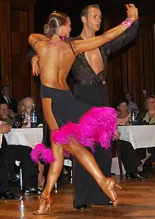 Image 18Latin dancers in their costumes. The woman is wearing backless dress with deep slits on its lower portion, while the man is wearing a shirt with top buttons open. (from Fashion)