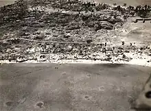 Aerial view of Betio, Tarawa Atoll, 24 November 1943, looking north toward "The Pocket", the last place of Japanese resistance. An emplacement just onshore with two 12.7 mm anti-aircraft guns is visible near the left edge of the photograph.