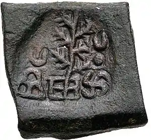 A coin of Takshashila, portrays a tree flanked by a hill surmounted by a crescent and a Nandipada above a swastika.