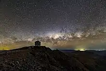 A night view of the Gemini South, the southern half of the international Gemini Observatory on Cerro Pachón with the Milky Way and streak of light left by a meteor in the background.