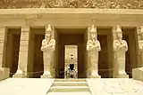 Tall stone statues of Hatshepsut with crossed arms holding a sceptre and a flagellum