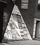 Smithsonian archive photo shows the unintended reality of Weathering Triangle as installed in Greenwich Village – covered over with unauthorized event posters and graffiti tags.