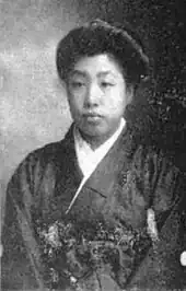 A young Japanese woman wearing a dark kimono with white near the neckline