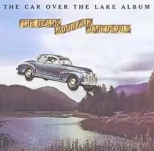 A vintage car flying over a mountain lake