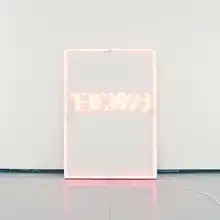 A photograph of a rectangular pink neon sign against a pale blue background, reading "The 1975".