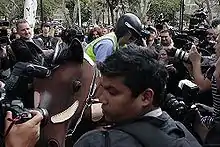 A pantomime horse is surrounded by media and police. Chaser member Chris Taylor is dismounting the obviously fake horse dressed like a police officer.