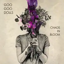 An art piece in beige with a woman holding flowers in front of her face that are purple