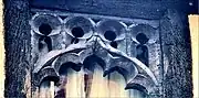 Close up of the top of a second floor window, which is made of old oak wood, cut into an arch with multiple semi circular foils