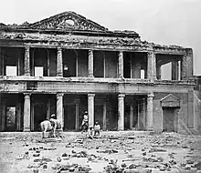 A photograph of the ruins of a palace with human skeletal remains in the foreground
