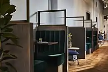 Green velvet chair with dark wood table and water glass