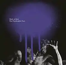 A black-and-white  photo of a sculpture of a man with a long beard covering his face with a large splatter of purple paint on the top and the album and band name in white type