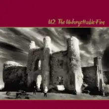 A black-and-white photo of a castle with the album and artist name written in dark crimson banners above and below it