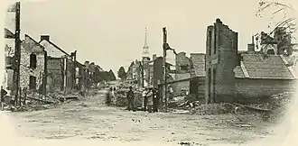 buildings destroyed by fire with people standing around