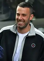 Ben Affleck, wearing a tracksuit top, smiles