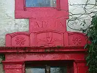 A view of the marriage stone lintel positioned over the entrance to 'The Hill' farm mansion house together with the motto "Delights and Adorns" and a Bible held in a hand dexter held upright, suggesting both northern Ireland and Protestantism.