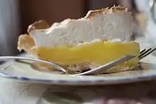 A slice of pie showing its crust, lemon curd filling, and meringue topping.