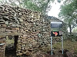 A picture of a stone wall with a gate.