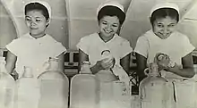 Three young, smiling Chinese women drying dishes