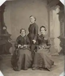 three women posing together for a portrait in 1876. the two on the left and right - Elizabeth Ann Whitney and Eliza R. Snow, respectively - are sitting, while the one in the middle - Emmeline B. Wells - stands