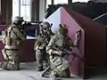 Three airsoft team members defending an area during an indoor CQB game.