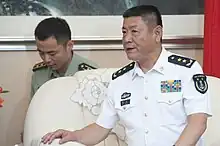 a man with a cropped haircut, wearing a white military uniform while looking leftwards (away from the camera)