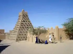 A picture of a very small pyramid with dozens of wooden poles sticking out around it.