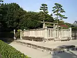 Torii beyond concrete fence.