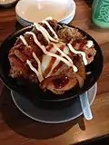 A bowl of Japanese rice topped with karaage chicken, soft-boiled egg, vegetables and topped with condiments