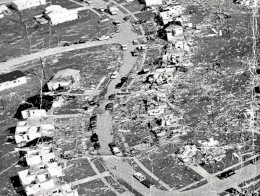 Black-and-white aerial photograph showing shattered homes and debris