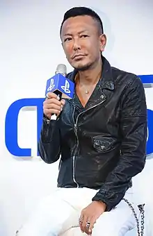 Toshihiro Nagoshi, seated, giving an interview.