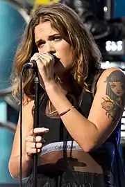 A woman with brown hair holding a microphone.