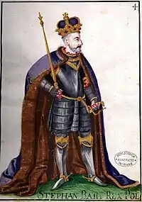 A bearded middle-aged man wearing a crown and armour