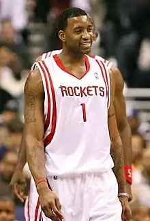 A man, wearing a white jersey with a word "ROCKETS" and the number "1" written in the front, is walking on a basketball court.