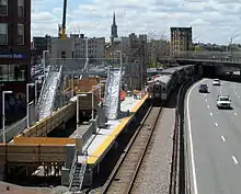 Railway platforms under construction next to an urban highway