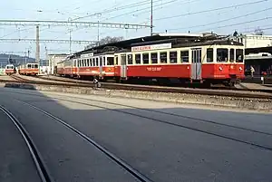 Red-and-cream-colored rail vehicles at a station