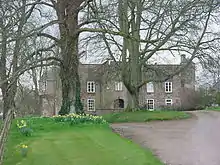 Photograph of a large country house surrounded by trees
