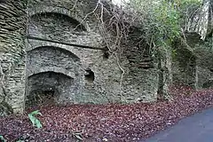 Stone kilns built into a bank with a road in front.