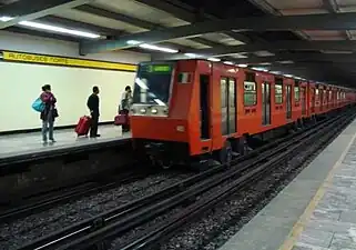 Picture of the platforms of Autobuses del Norte featuring a NM-83 train, an orange rubber-tired model used by the Mexico City Metro stystem.
