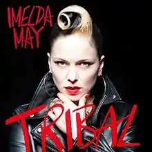 An image of a woman in a black leather jacket staring into the camera, with her hand elevated to her chin. Block handwritten text in red reads "Imelda May" to the top left and "Tribal" to the centre-bottom.