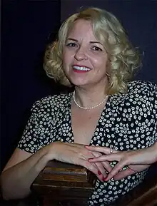 A woman with blond hair, wearing a black and white outfit.