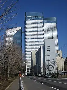 Ground-level view of a three-building complex; each building is white and blue and lined with rows of windows