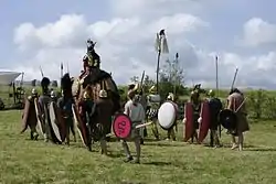 A group of men dressed in clothes and carrying weapons from the 3rd century BC accompanying a medium-sized elephant