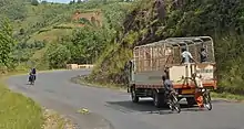 two bicyclists hold on to back of truck descending a hill
