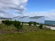 a modern building with sloping roof and the sea in the background