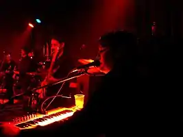 The band onstage performing with dark red lighting