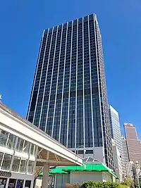 A color photograph of a skyscraper in front of a blue sky