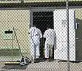 Two detainees in white "uniforms" stand in the doorway of their bay in Camp 4.