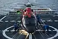 Flight deck crew members aboard Bertholf tie down an MH-65 Dolphin helicopter.
